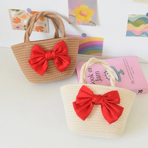 Handmade woven straw handbags in beige and white with large red satin bow details