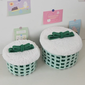 Detail of two-piece cylindrical storage baskets with green checkered pattern and white plush lids