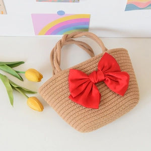Top view of beige straw handbag with large red satin bow and decorative tulips