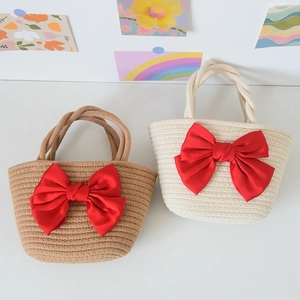 Close-up of hand-woven straw bags with large red satin bows for wedding favors