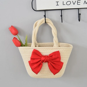 Detail of woven straw handbag with a large red satin bow and braided handle grip