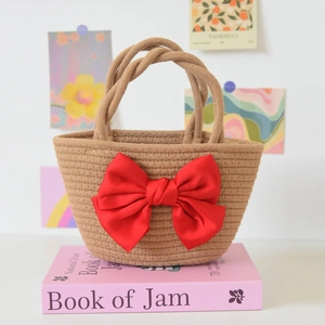 Close-up of woven hand-held gift bag featuring a large decorative red satin bow