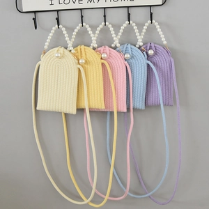 Detailed macro of handmade woven mini phone bags in five macaron colors with pearl handles