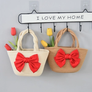 Handmade straw woven tote bag with large red satin bow and braided handle for beach vacation