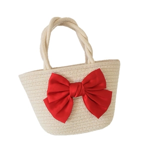 Chic cream woven straw handbag featuring a large decorative red satin bow for beach vacation