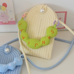 Detail of woven mini crossbody bag featuring pearl button and embroidered plush charm