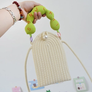 Detail of hand-woven phone bag featuring a large pearl clasp and green embroidered handle