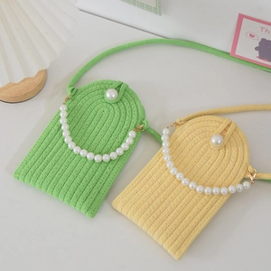 Detail of hand-woven mini crossbody phone bags with pearl handles and pearl buttons