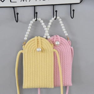 Detail of handmade woven pearl mini crossbody bags in vibrant yellow and soft pink colors