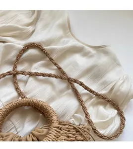Detail of hand-woven straw bag featuring a stylish braided shoulder strap and drawstring