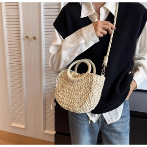 Detail of hand-woven beige straw bucket bag with drawstring liner and thick shoulder strap