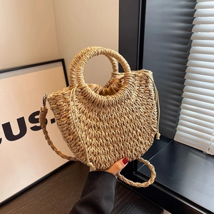 Detail of a semi-circular woven straw bag with sturdy round handles and a drawstring closure