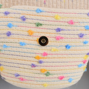 Close-up of handmade woven beach bag with colorful pom-poms and gold magnetic clasp