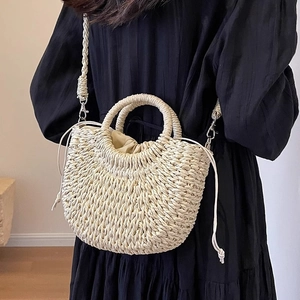 Detail view of woven straw bag with drawstring liner and silver metal hardware accents