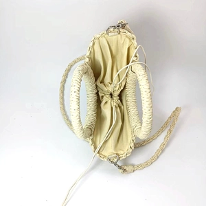 Detailed view of beige woven straw tote bag with drawstring inner pouch and round handles