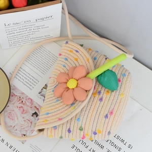 Detail of children's straw bag with colorful pompoms and large pink fabric flower ornament