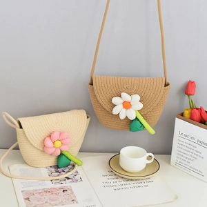 Detailed view of woven straw mini cross-body bags with plush floral accents and cord straps