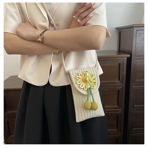 Detail of hand-knitted beige crossbody bag with floral accents and soft texture
