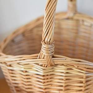 Detailed view of handmade wicker basket handle with reinforced weaving and natural wood texture