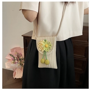 Detail of hand-woven crossbody cell phone bag with floral decorations and textured knit