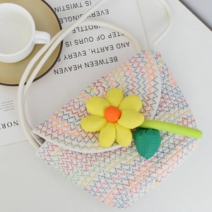 Detail of hand-woven mini crossbody bag featuring a 3D yellow flower and colorful wavy patterns