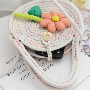 Détail d'un sac tissé en coton avec fleurs orange en tissu et fermeture par bouton en bois