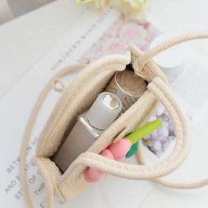 Détail montrant l'intérieur spacieux d'un sac en paille beige avec décor floral coloré
