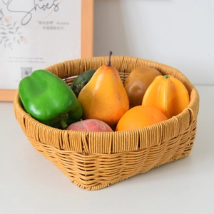 Close-up of woven rattan fruit basket with artificial vegetables on a white tabletop