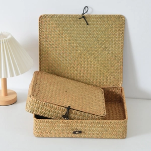 Detail of two handmade seagrass storage boxes with lids and black elastic fasteners