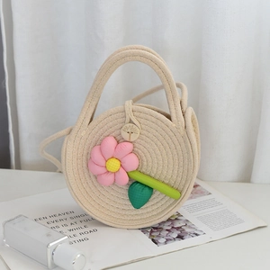 Détail de la fermeture à bouton en bois vintage et décor floral sur un sac tissé