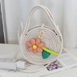Détail d'un sac tissé avec surpiqûres arc-en-ciel et décoration de fleur en tissu 3D