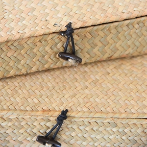 Macro detail of the natural seagrass woven box featuring an elastic loop and horn button