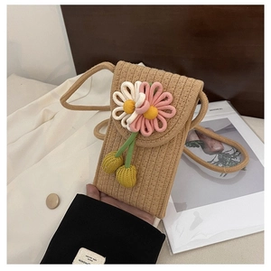 Detail of hand-held straw phone bag with pink fabric flower and woven pendant