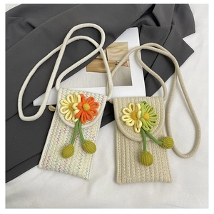 Detail of woven straw phone bags featuring sunflower embellishments and thick rope straps