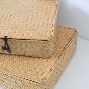 Detailed close-up of natural woven grass storage box with elegant wooden toggle closure