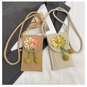 Detail of woven straw phone bags with handmade floral accents in khaki and beige tones
