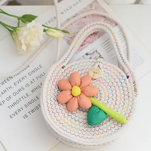 Détail du sac tissé avec accents floraux 3D et fermeture par un bouton en bois