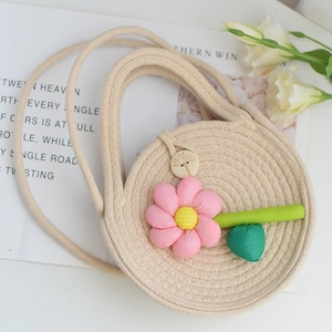 Détails du sac tressé avec fleur en tissu et fermeture par bouton en bois gravé