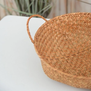 Detail of hand-woven natural seagrass storage basket with reinforced handles and texture