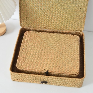 Detail of handwoven seagrass storage boxes with button closure in a minimalist desk setting