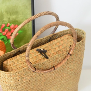 Nahaufnahme einer handgewebten Strohtasche mit rustikalem Holzverschluss und Rundgriffen