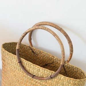 Detailansicht der gewebten Strohtasche mit runden Holzgriffen und natürlicher Textur
