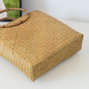 Detail einer handgeflochtenen Strohtasche mit runden Holzgriffen und Naturfaserstruktur