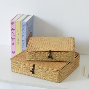 Detail of two handmade seagrass storage boxes with lids and wood toggle closures