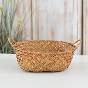 Detail of hand-woven natural seagrass storage basket with dual handles on a white surface