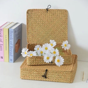 Detail of two-piece handmade straw storage boxes with woven textures and daisy decor