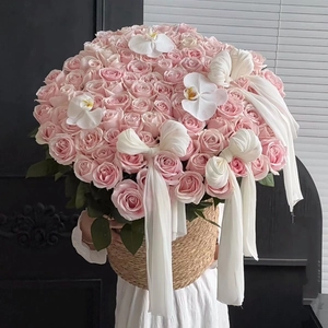 Detail of round straw flower basket with pink roses, white orchids and chiffon bow
