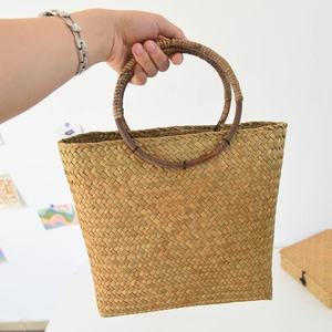 Detail einer handgewebten Strohtasche mit stabilen runden Holzgriffen für den Alltag
