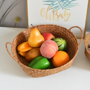 Detail of hand-woven seagrass basket with sturdy handles and decorative artificial fruit
