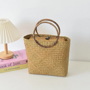 Detail einer Vintage-Stroh-Handtasche mit runden Holzgriffen und sicherem Knopfverschluss